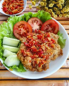 a white plate topped with lettuce and tomatoes next to cucumber slices