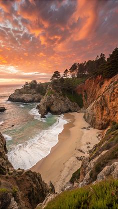 the sun is setting over an ocean with rocks and trees in the foreground, along with waves crashing on the shore