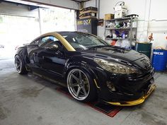 a black sports car parked in a garage with yellow rims on it's tires