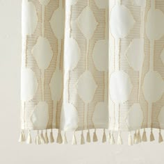 a curtain with tassels hanging from it's side in front of a white wall