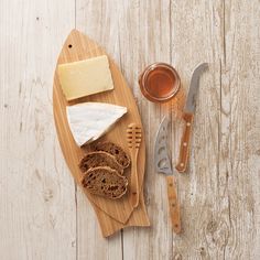 bread, cheese and butter are on a cutting board with utensils next to it