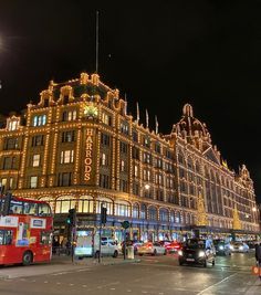 a very big building with some lights on it's sides and cars driving down the street