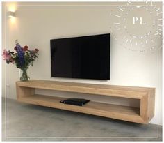 a large flat screen tv mounted to the side of a wall next to a vase with flowers