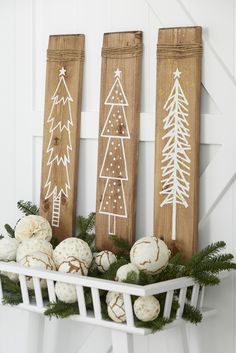 three wooden signs with christmas trees on them and balls in the foreground are pine cones