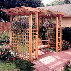 a wooden bench sitting under a pergoline covered arbor in a yard with lots of flowers