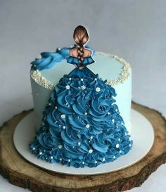 there is a blue cake that looks like a dress on top of a tree stump