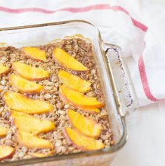 baked oatmeal with sliced peaches in a glass dish on a towel