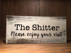 a wooden sign that says, the shitter decor please enjoy your visit on it