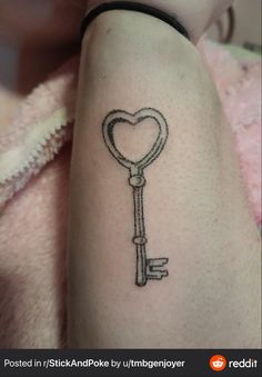 a heart shaped key tattoo on the arm