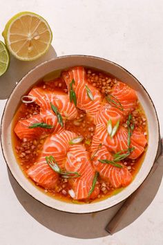 a bowl filled with salmon and beans next to a lemon slice