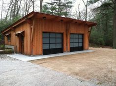 two garages in the middle of a wooded area with gravel and rocks around them