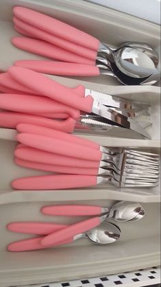 pink utensils are in the holder with spoons and forks