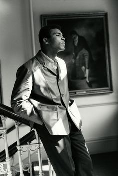 a black and white photo of a man in a suit standing at the top of stairs