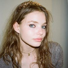 a young woman with blue eyes wearing a gold tiara on top of her head