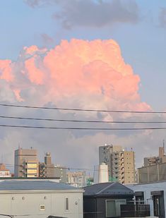 the clouds are pink and fluffy in the sky above some buildings with power lines running through them