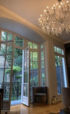 a chandelier hanging from the ceiling in a living room with french doors and windows