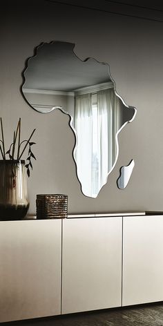 a mirror that is on the side of a cabinet next to a vase with flowers in it