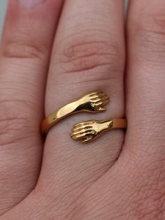 a person's hand with two gold rings on it, one is holding the other