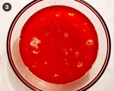 a bowl filled with red liquid on top of a white table