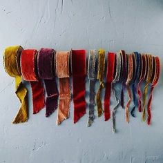 multicolored scarves hanging on the wall in a row with fringes attached to them