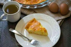 a piece of pie on a plate next to a cup of tea and an egg