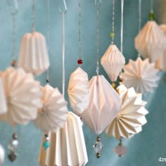 some white origami ornaments are hanging from the ceiling in front of a blue wall