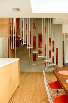 a kitchen with wooden floors and red chairs next to a counter top in front of a spiral staircase