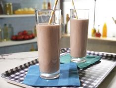 two glasses filled with chocolate milkshakes on top of a blue and white checkered napkin