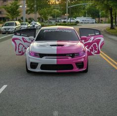 two pink and white cars parked on the side of a road next to each other