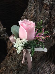 a pink rose and white flowers tied to a tree