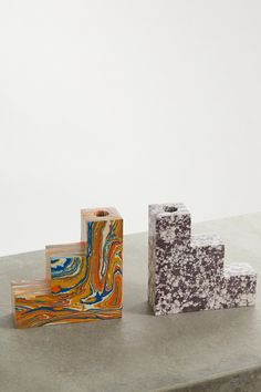 three different types of marble blocks sitting on top of a cement slab, one is orange and the other is blue