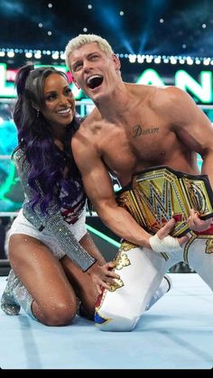 a man and woman posing for a photo in front of a wrestling ring with their arms around each other