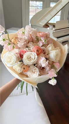 a bouquet of flowers sitting on top of a table next to a white piano in a room