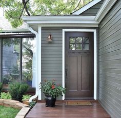 a house with a potted plant on the front porch next to it's door