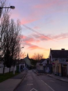 the sun is setting on an empty street