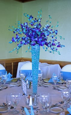 a blue vase filled with purple flowers sitting on top of a table covered in silverware