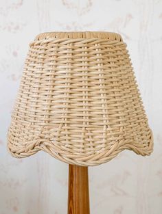 a wicker lamp shade sitting on top of a wooden table next to tulips