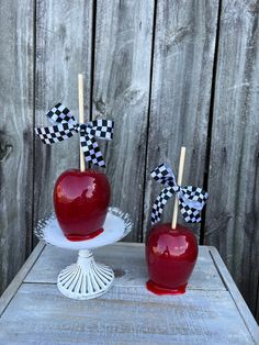 two red apples sitting on top of a cake plate with checkered flags sticking out of them