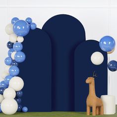 a giraffe is standing in front of balloons on the wall and an arch