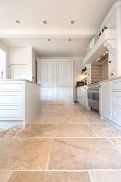 an empty kitchen with white cabinets and tile flooring