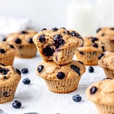 blueberry muffins stacked on top of each other with a glass of milk in the background