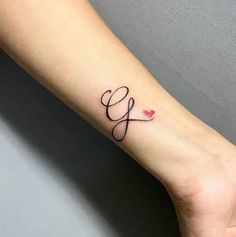 a woman's wrist tattoo with the letter g in cursive writing on it