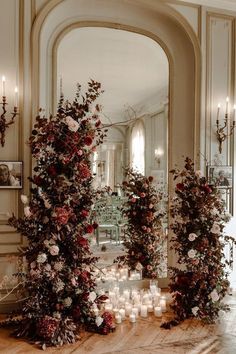 candles and flowers are arranged on the floor in front of an ornate arch with mirrors