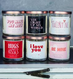 four candles are sitting next to each other on a shelf with the words, you light up my world and i love you be mine