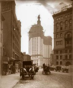 an old photo of horse drawn carriages on a city street with tall buildings in the background