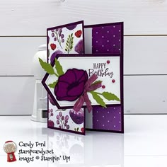 a close up of a greeting card with a purple flower and green leaves on it