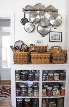 an organized pantry with lots of pots and pans on the wall next to baskets