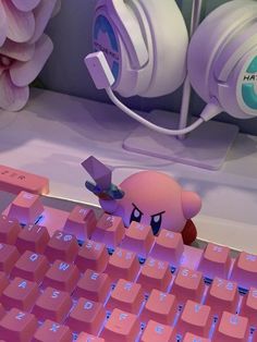 a pink teddy bear sitting on top of a keyboard with headphones over its ears