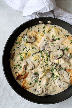 a skillet filled with food on top of a white tablecloth next to a napkin