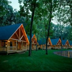 a row of cabins in the woods at night with lights on and trees surrounding them